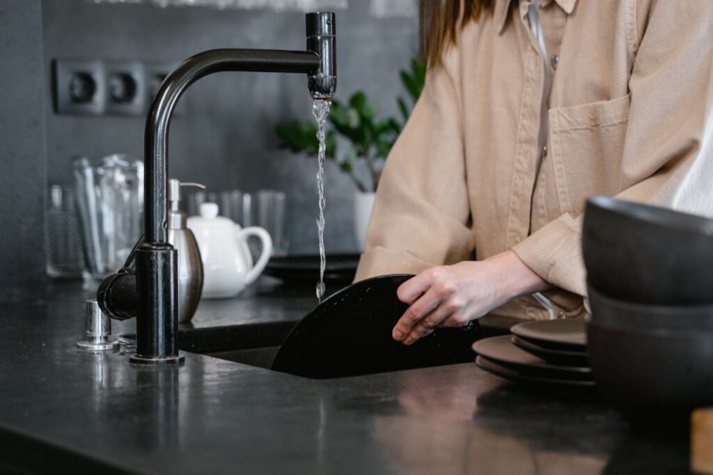 Close-up of a person washing their dishes using one of the many luxury faucets and fixtures available