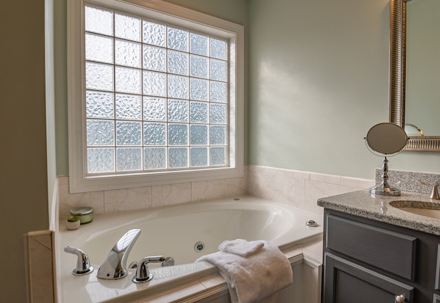 A bathroom with a white ceramic tub and a big window