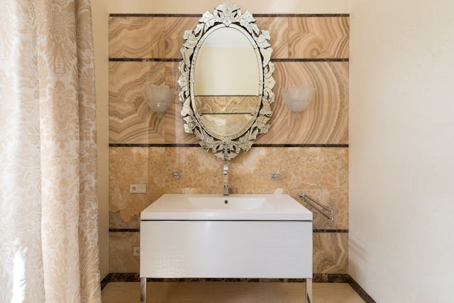 A vintage, oval-shaped mirror above a sink