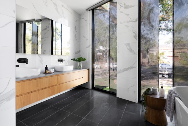 A bathroom with black floor tiles and two large windows