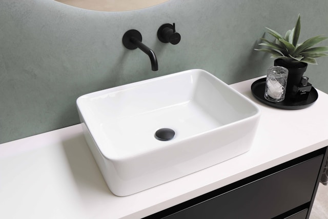 A white ceramic sink with black fixtures above