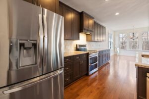 Contemporary kitchen with dark wood cabinetry, stainless steel appliances, and polished countertops.