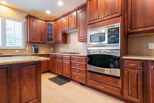 Warm-toned kitchen with wooden cabinetry, granite countertops, and modern appliances in a cozy space.